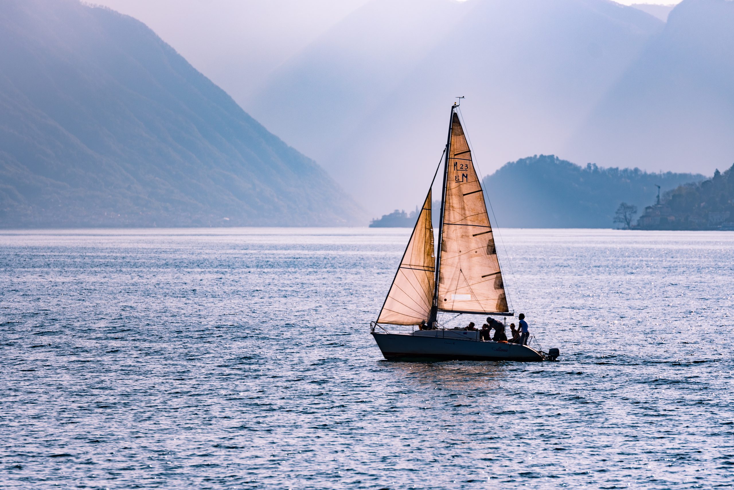Beautiful shot of a sailing boat travelling across the sea surrounded by mountains