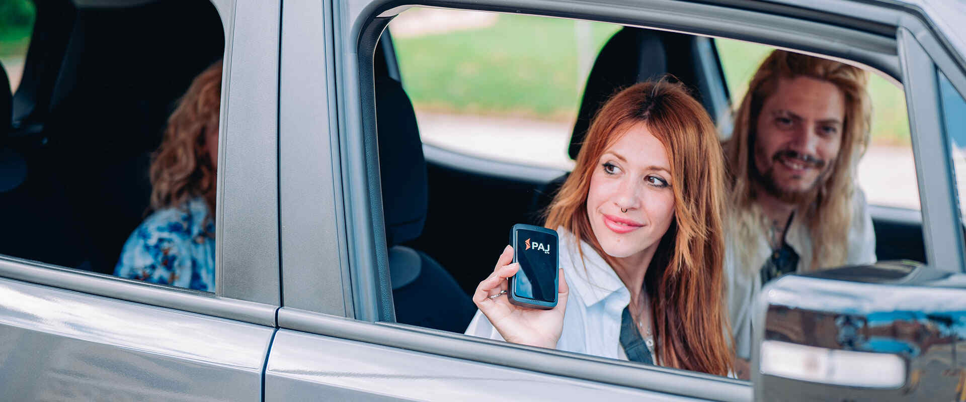 A girl sitting in car showing paj gps tracker in her hands
