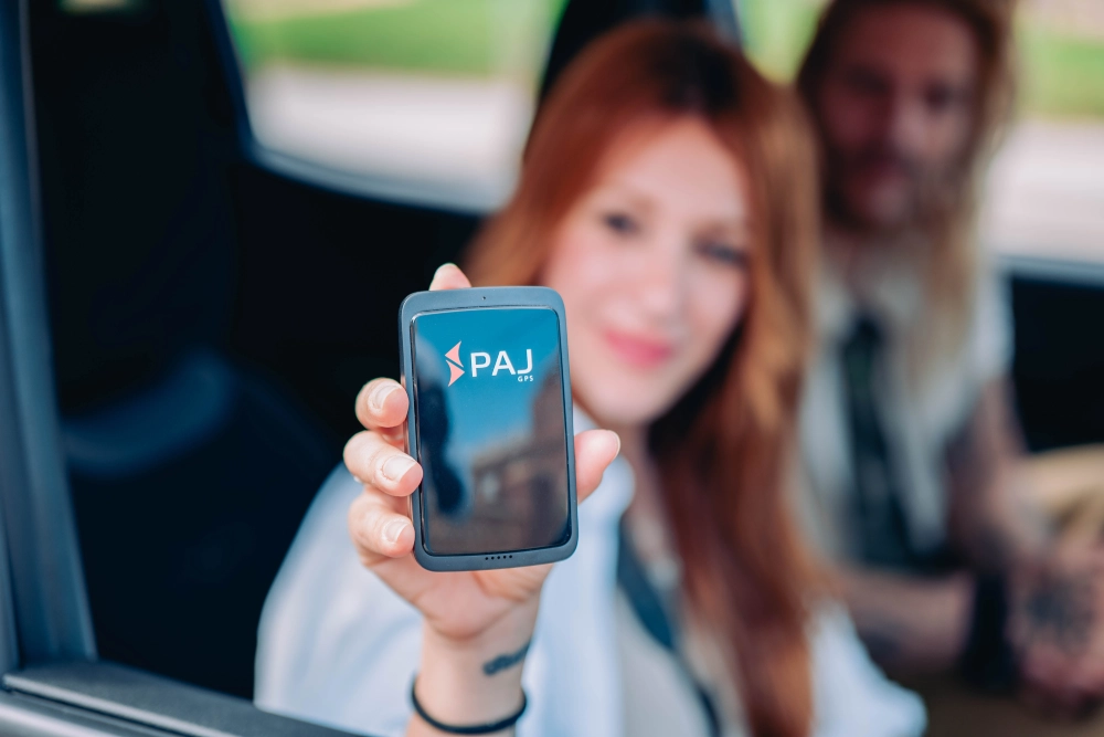 Lady sitting in a car holding allround finder 4g gps tracker